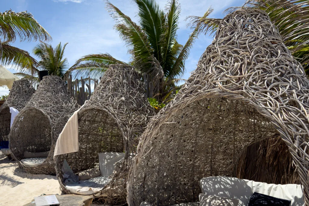 Woven wicker structures in the shape of cocoons on Tulum's beach, one of the relaxing highlights in "things to do in Tulum".